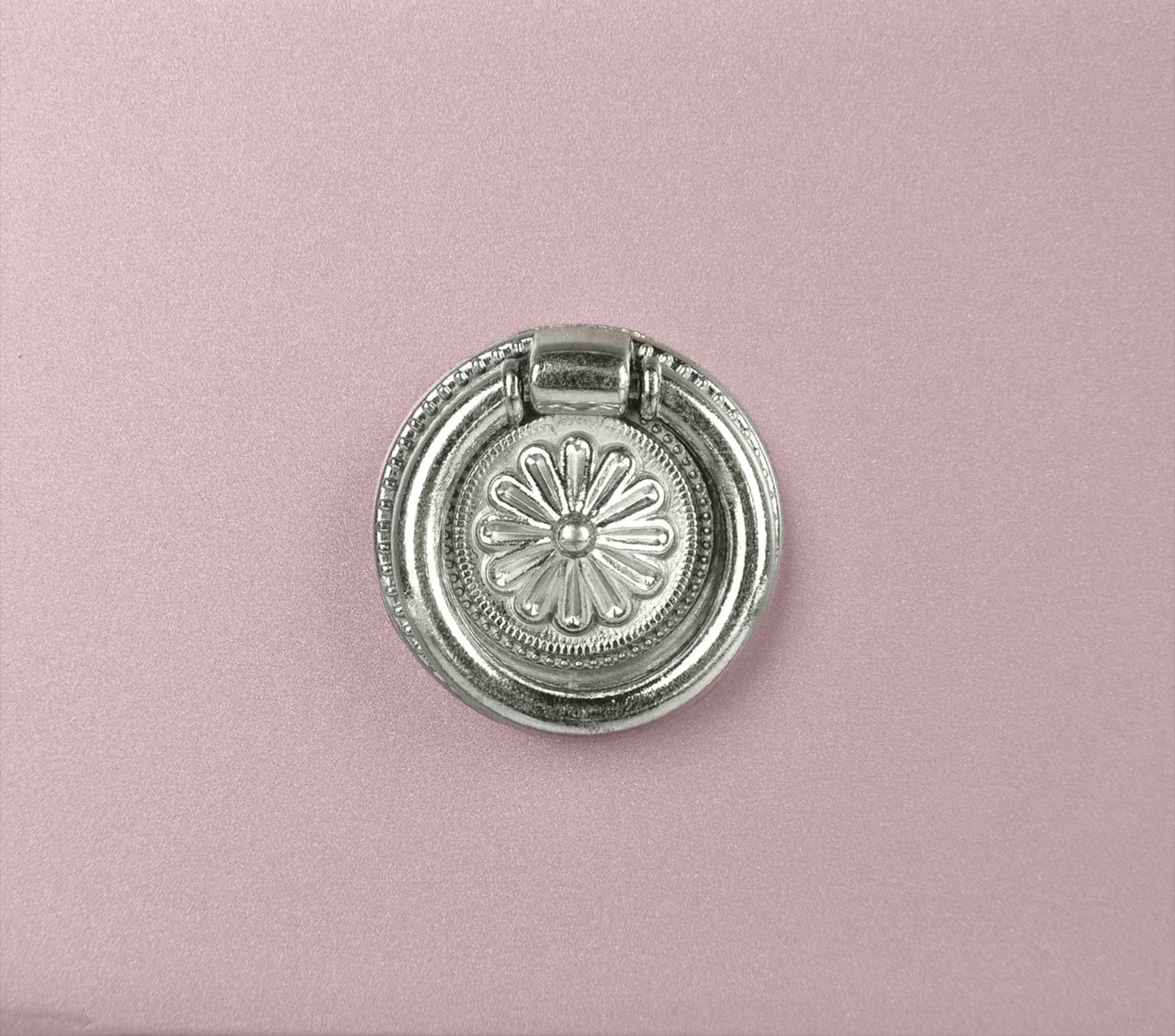 Silver ornate drawer pull with floral design on pink cabinet