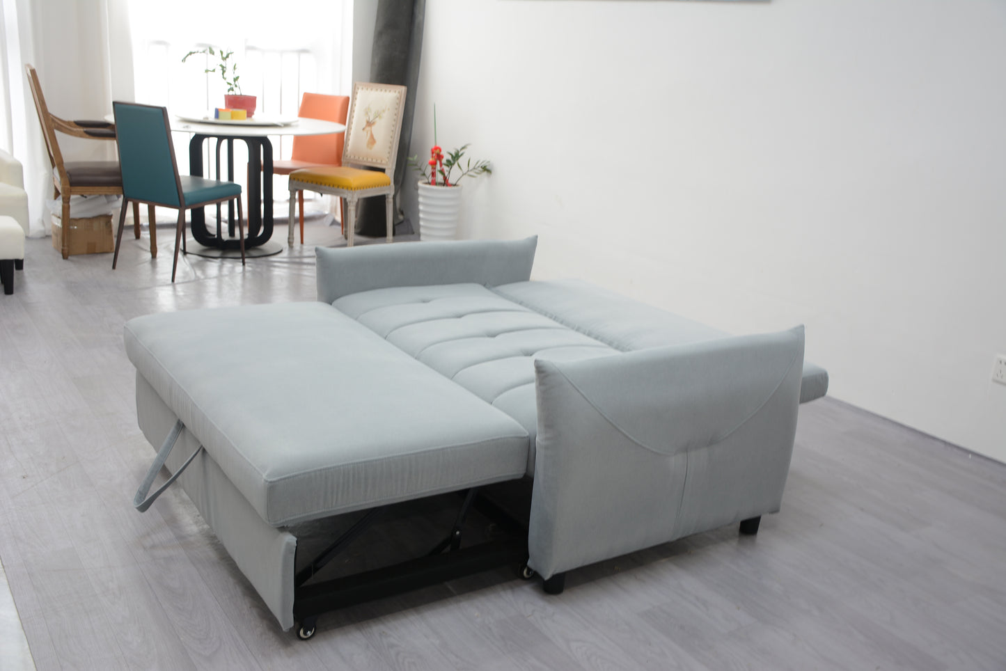 Light grey sofa bed with extended chaise lounge and tufted cushions
