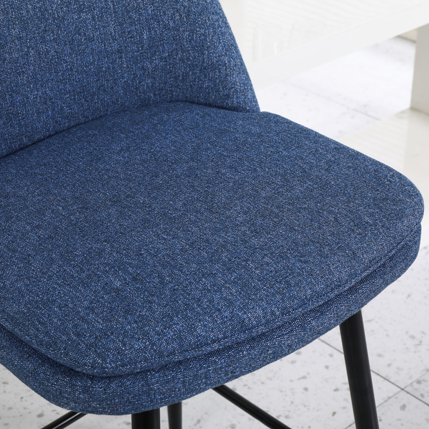 Textured blue upholstered seat and back of a modern dining chair with black legs