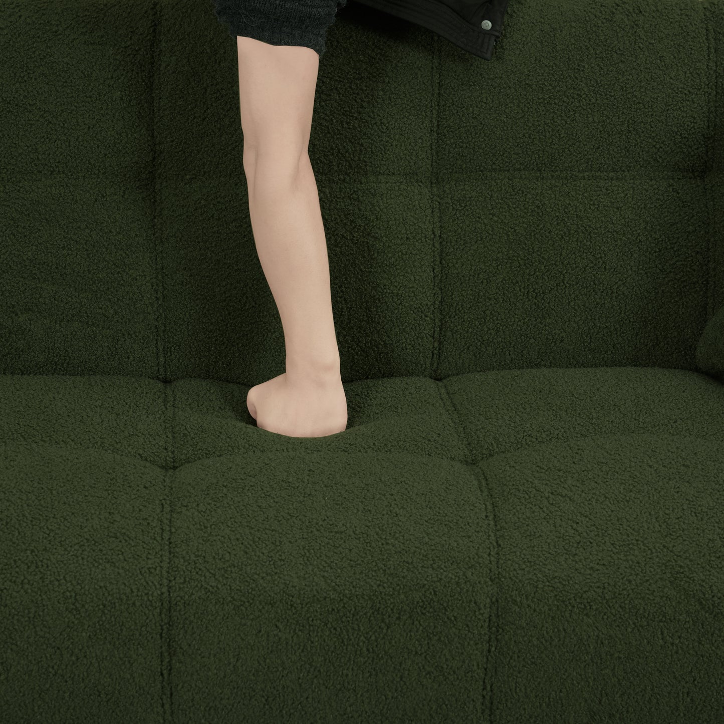 Deep green teddy fabric sofa with tufted seat and a childs leg pressing into cushion