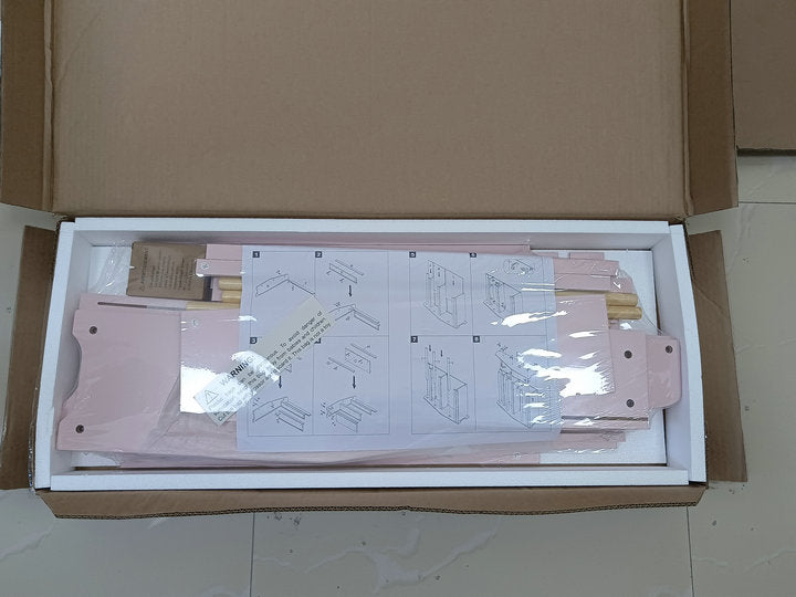 Pink wooden toddler bed frame components laid out in a box with assembly instructions