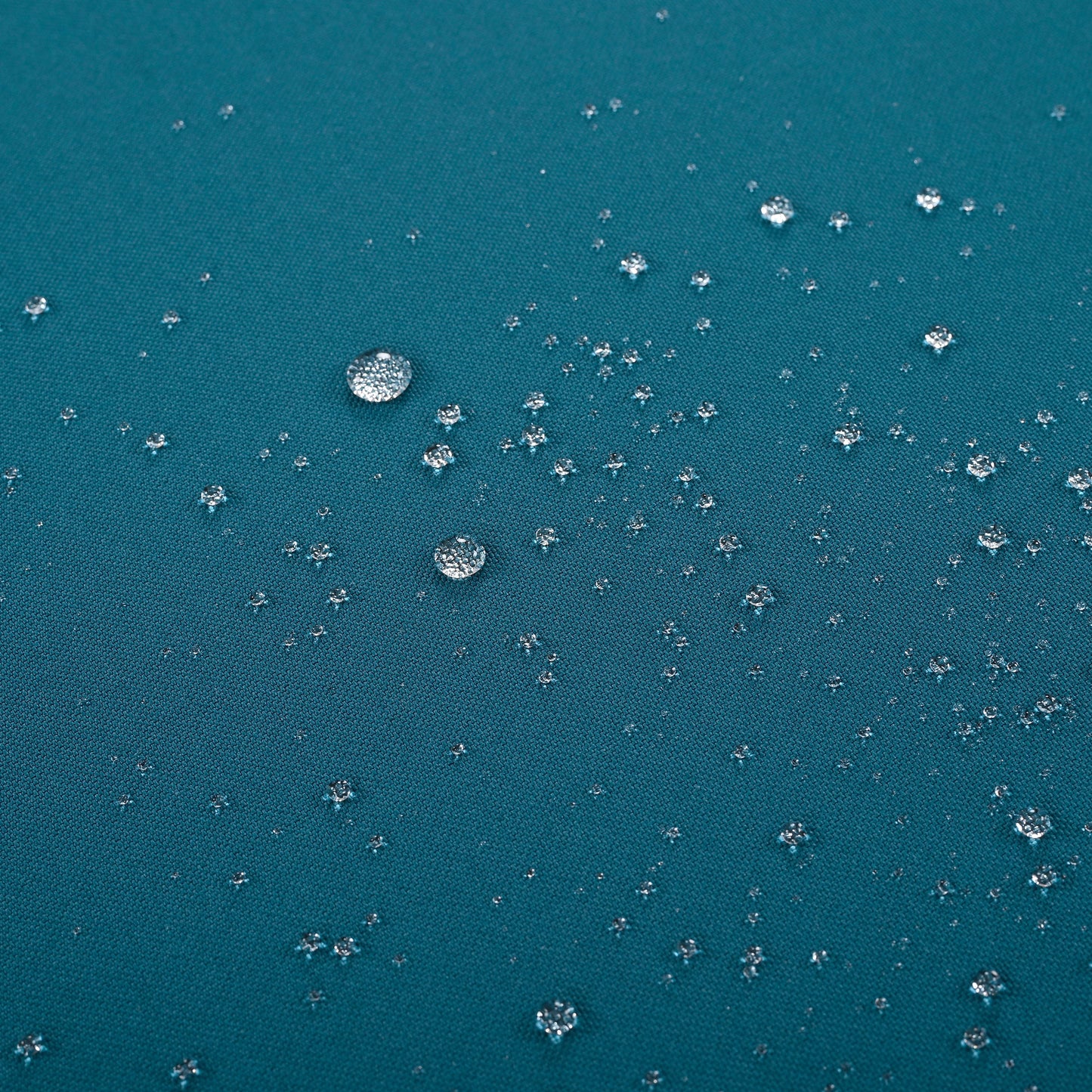 Teal fabric showing small water droplets beading on its waterproof surface