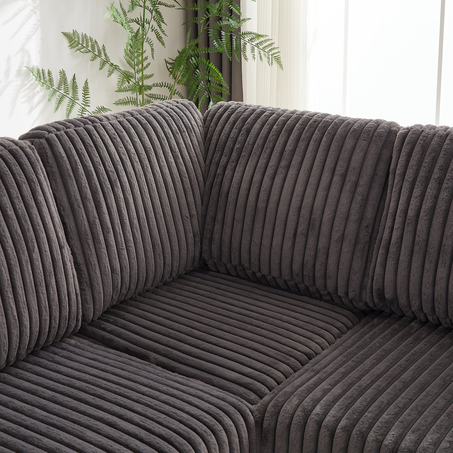 Closeup of a plush dark grey corduroy fabric sofa showcasing its textured ridges and soft feel