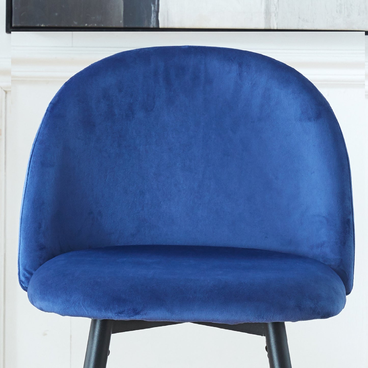 Close up of a plush royal blue velvet chair with a curved back and seat