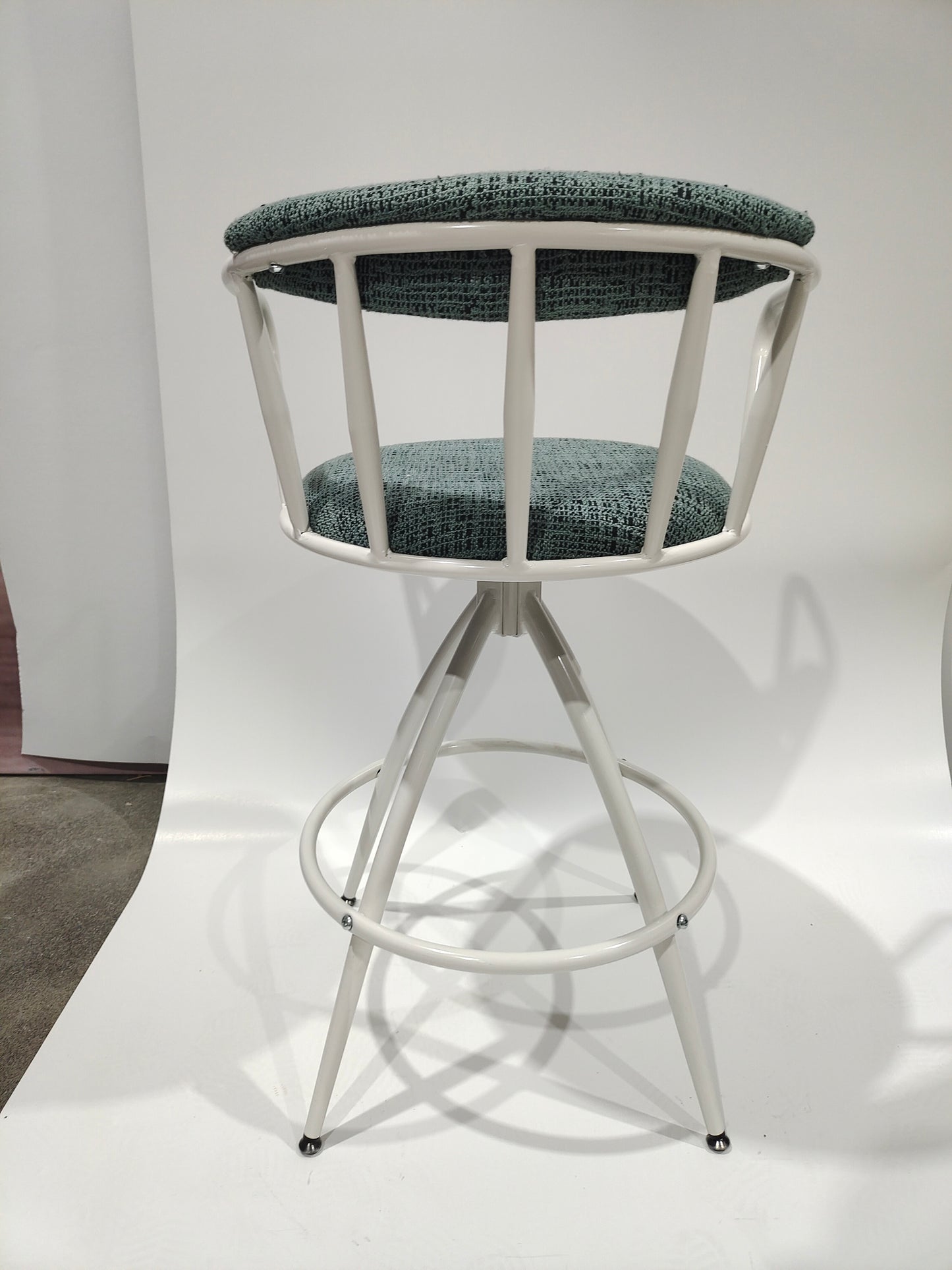 Sage green upholstered white metal swivel bar stool with crisscross back detail
