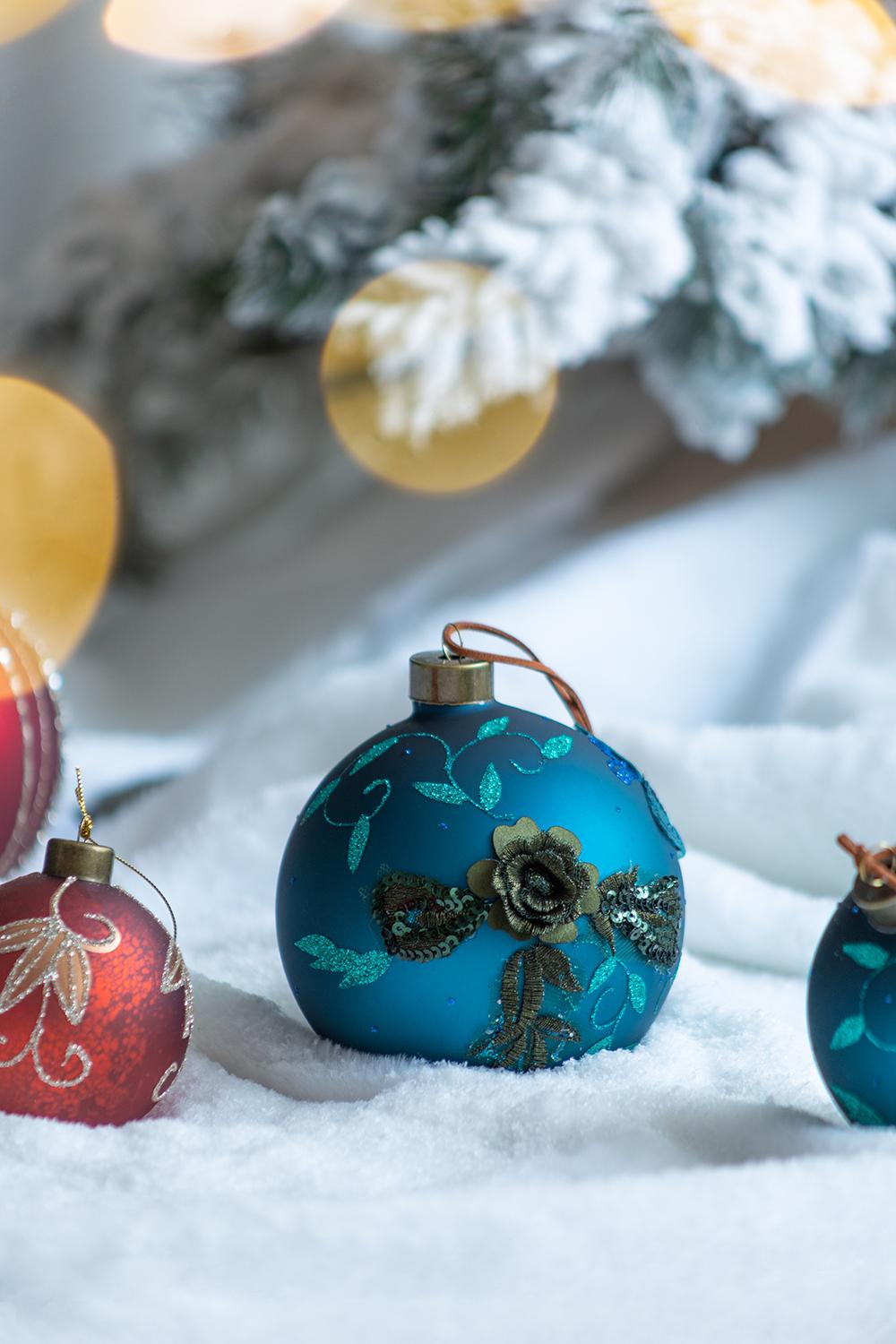 Teal glass Christmas ornament with gold floral detail and glitter accents