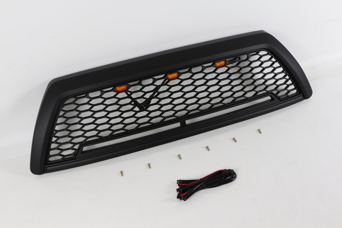 Black honeycomb truck grille with amber accent lights and mounting hardware