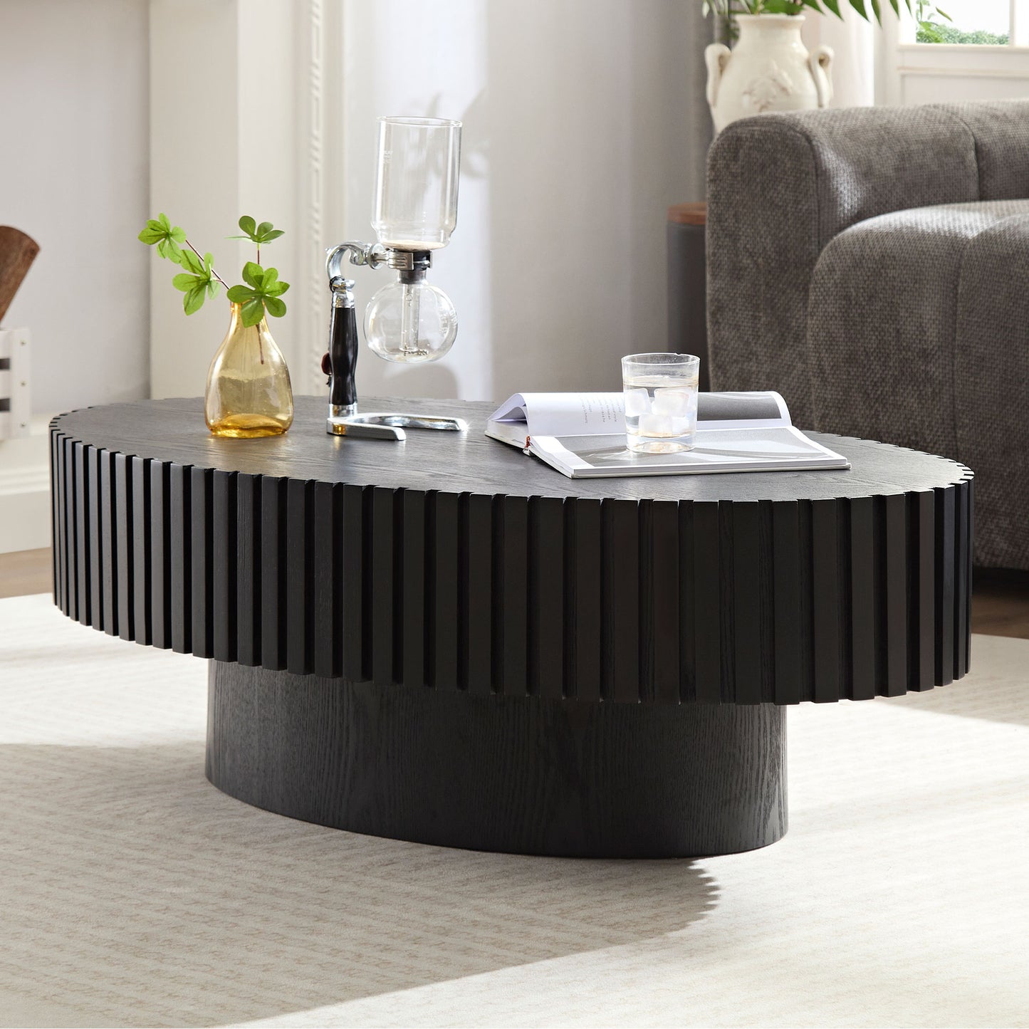Black oval coffee table with fluted wood design and pedestal base