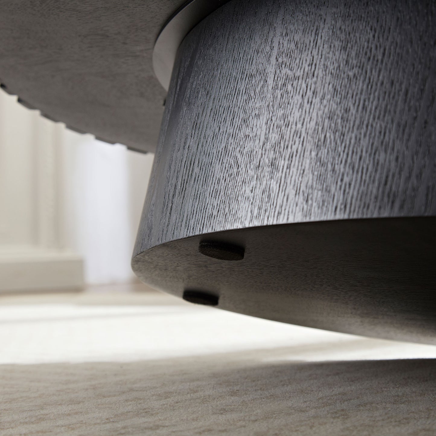 Dark gray oak textured pedestal base of a coffee table with protective floor pads
