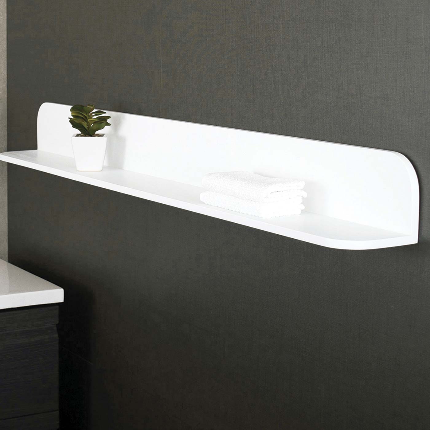 Modern floating white shelf with rounded edges displaying decorative plant and folded towels