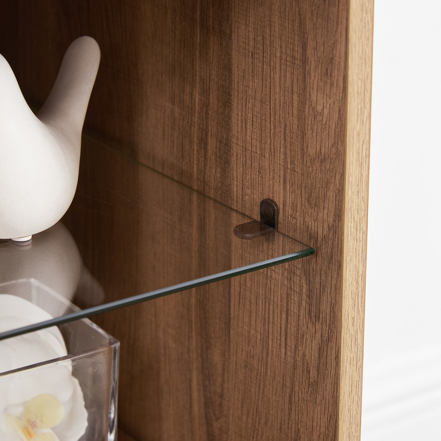 Closeup of clear glass shelf with metal support on textured wood cabinet