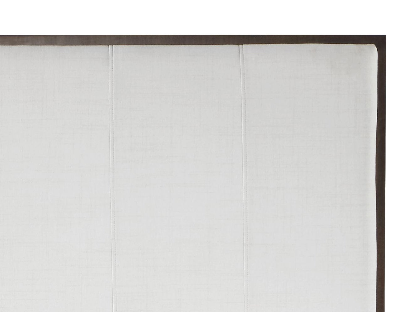 Closeup of a tufted ivory linen upholstered headboard panel with dark wood trim