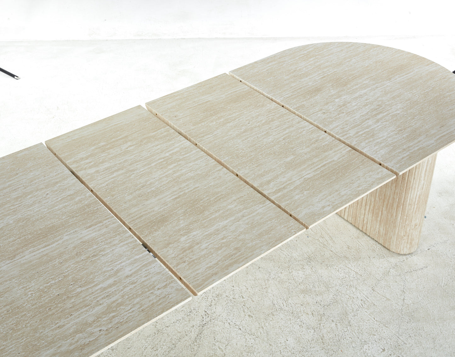 Extendable travertine dining table with natural stone texture and a rounded end