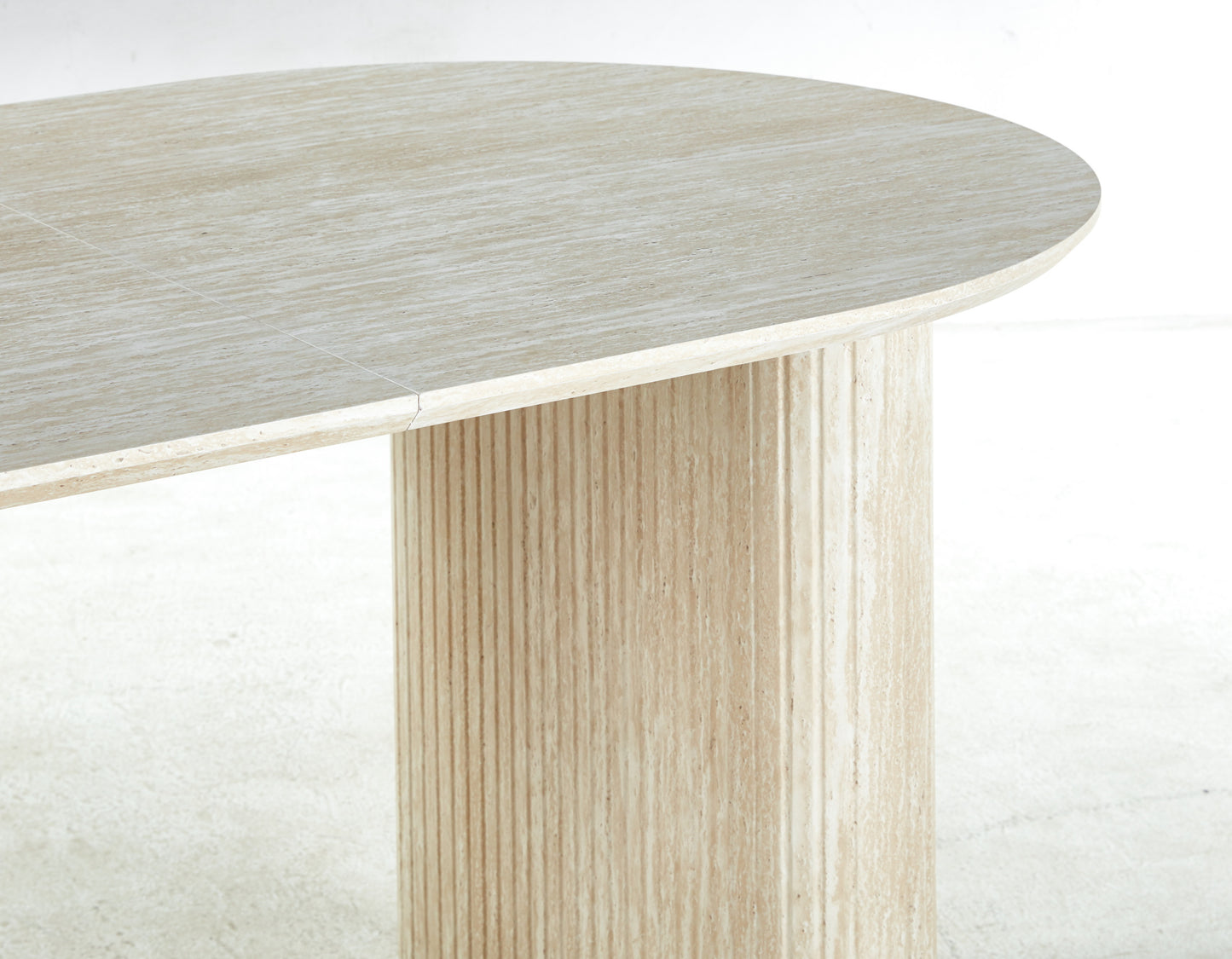 Beige travertine dining table with a smooth oval top and fluted pedestal base