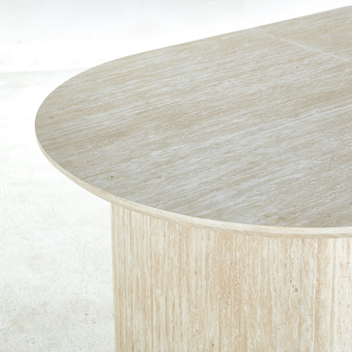 Oval travertine dining table with natural veining and a brushed finish