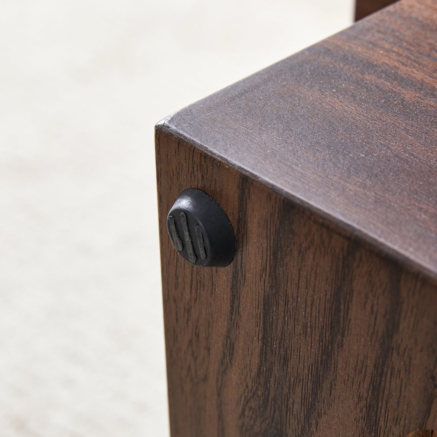 Dark wood grain texture on furniture leg with black antislip foot