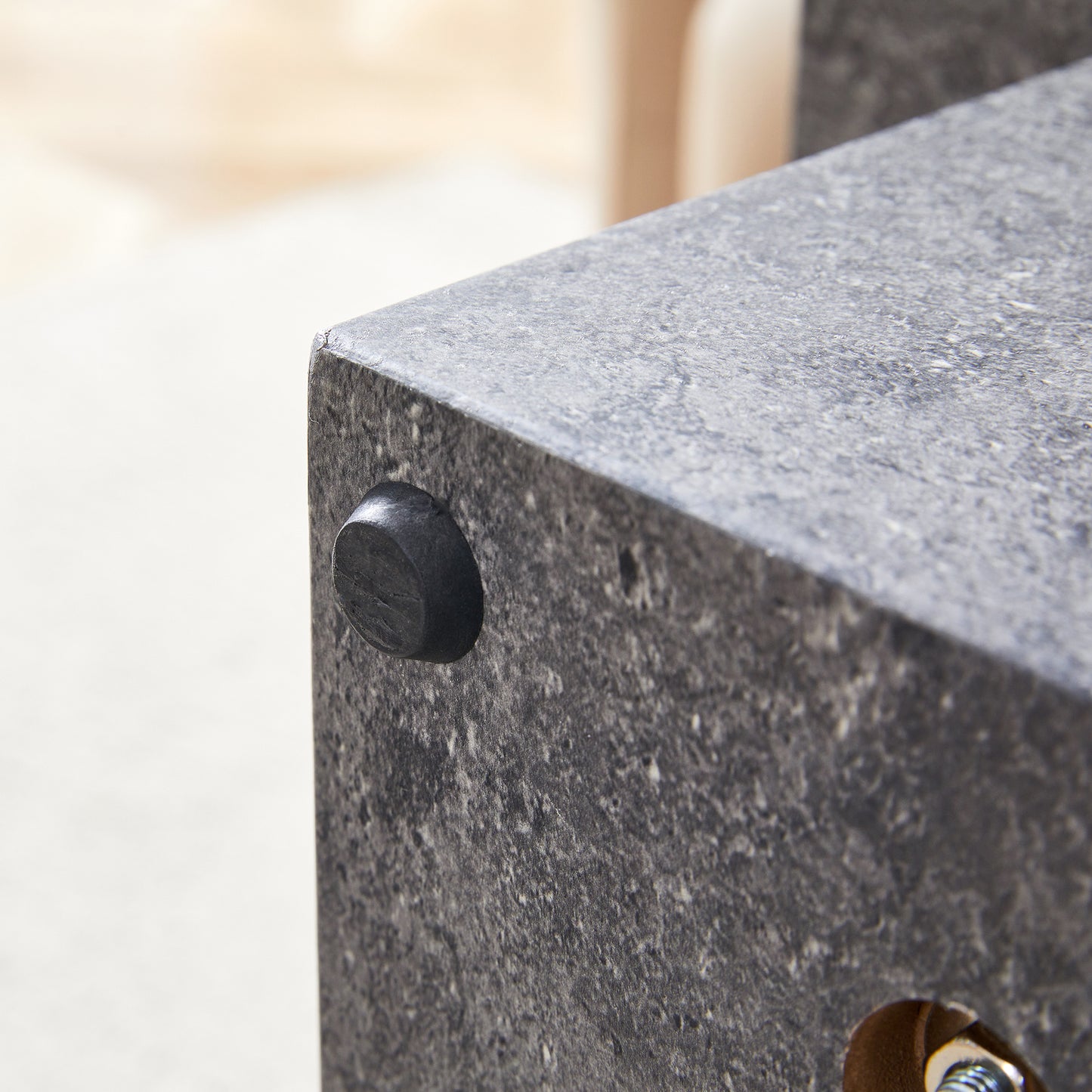 Close up of a dark gray stone effect table leg with a black rubber foot