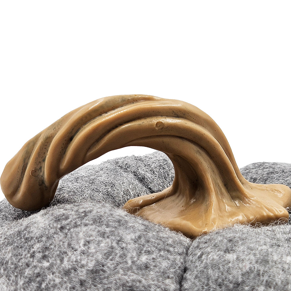 Textured tan chew toy with braided design on grey fuzzy fabric dog bed