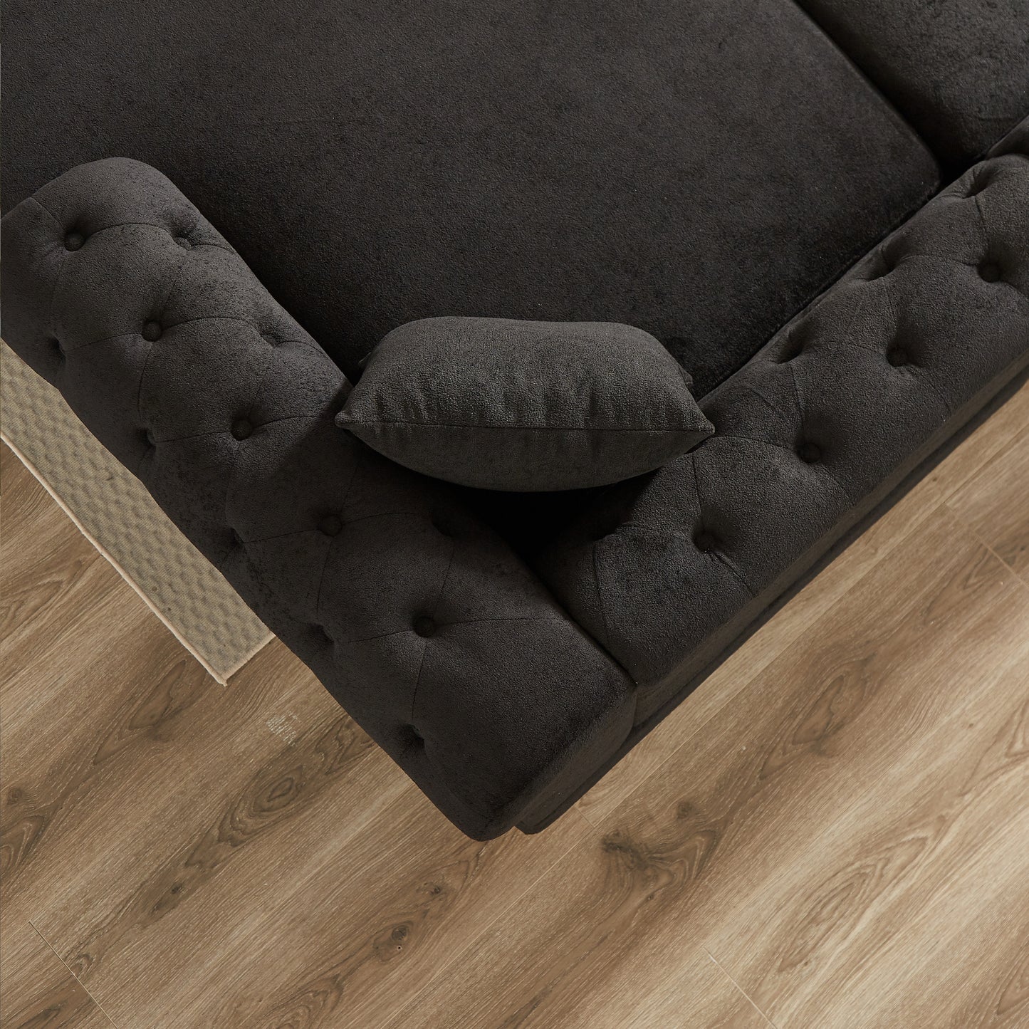 Dark grey fabric chesterfield sofa corner with tufted details and lumbar pillow