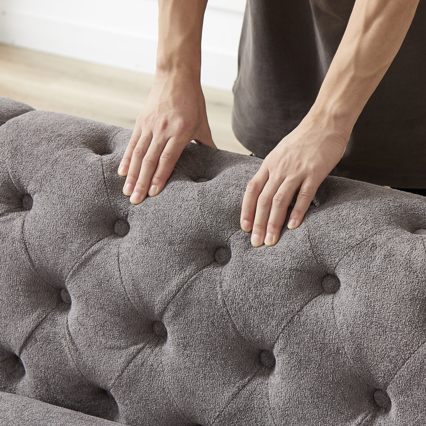 Closeup of tufted grey fabric sofa armrest with plush texture