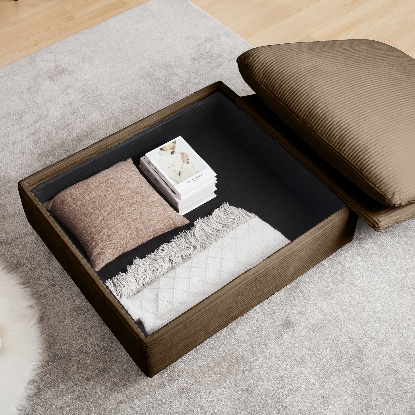 Brown corduroy ottoman with open storage holding books and throw blanket