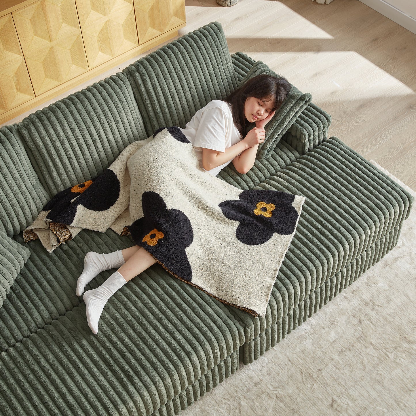 Cozy sage green corduroy sofa with a woman napping peacefully