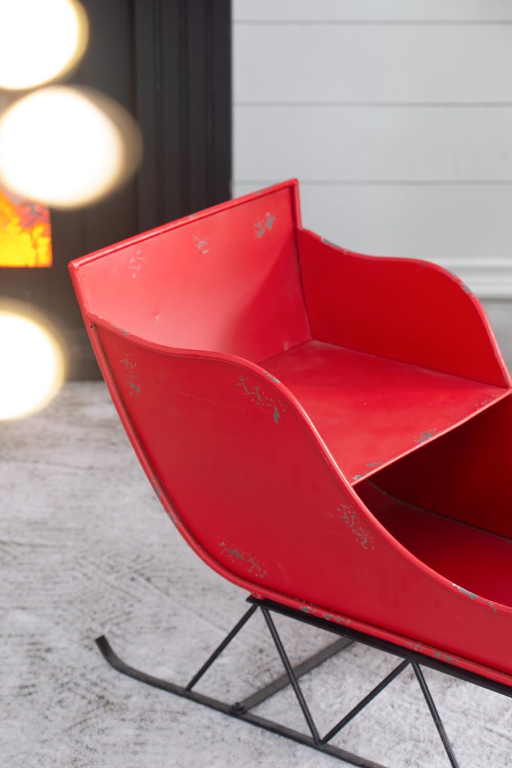 Small red metal sleigh with rustic distressed finish and black metal runners