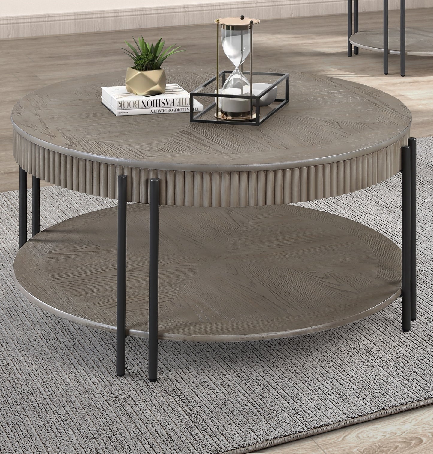 Round wooden coffee table with fluted sides and two tiers featuring dark metal legs and a herringbone top