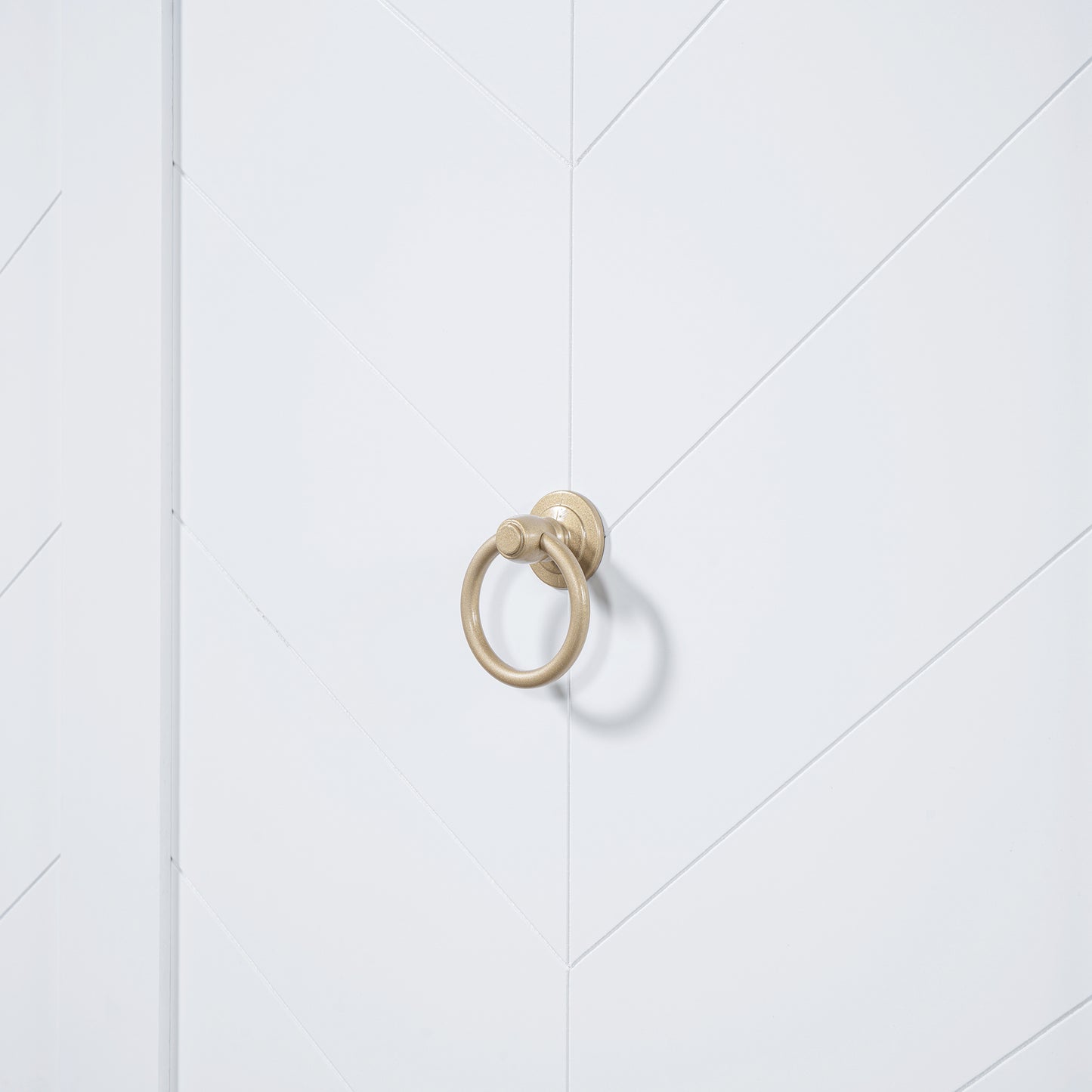 Antique brass ring pull on a white chevron patterned door