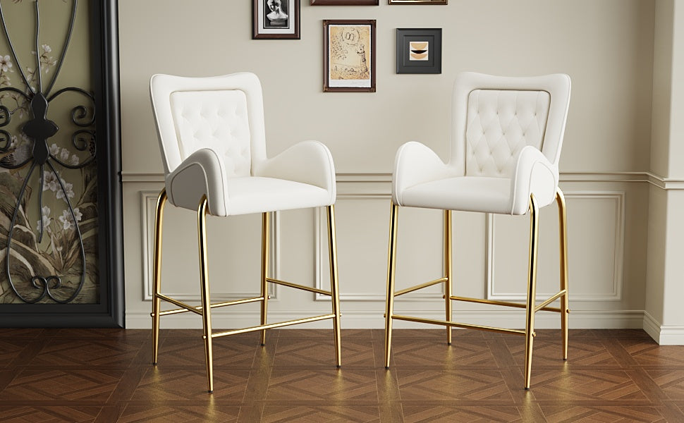 Two white velvet bar stools with gold legs and tufted backrests