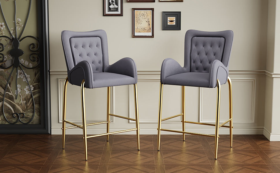 Two gray velvet tufted bar stools with gold legs perfect for a modern kitchen island
