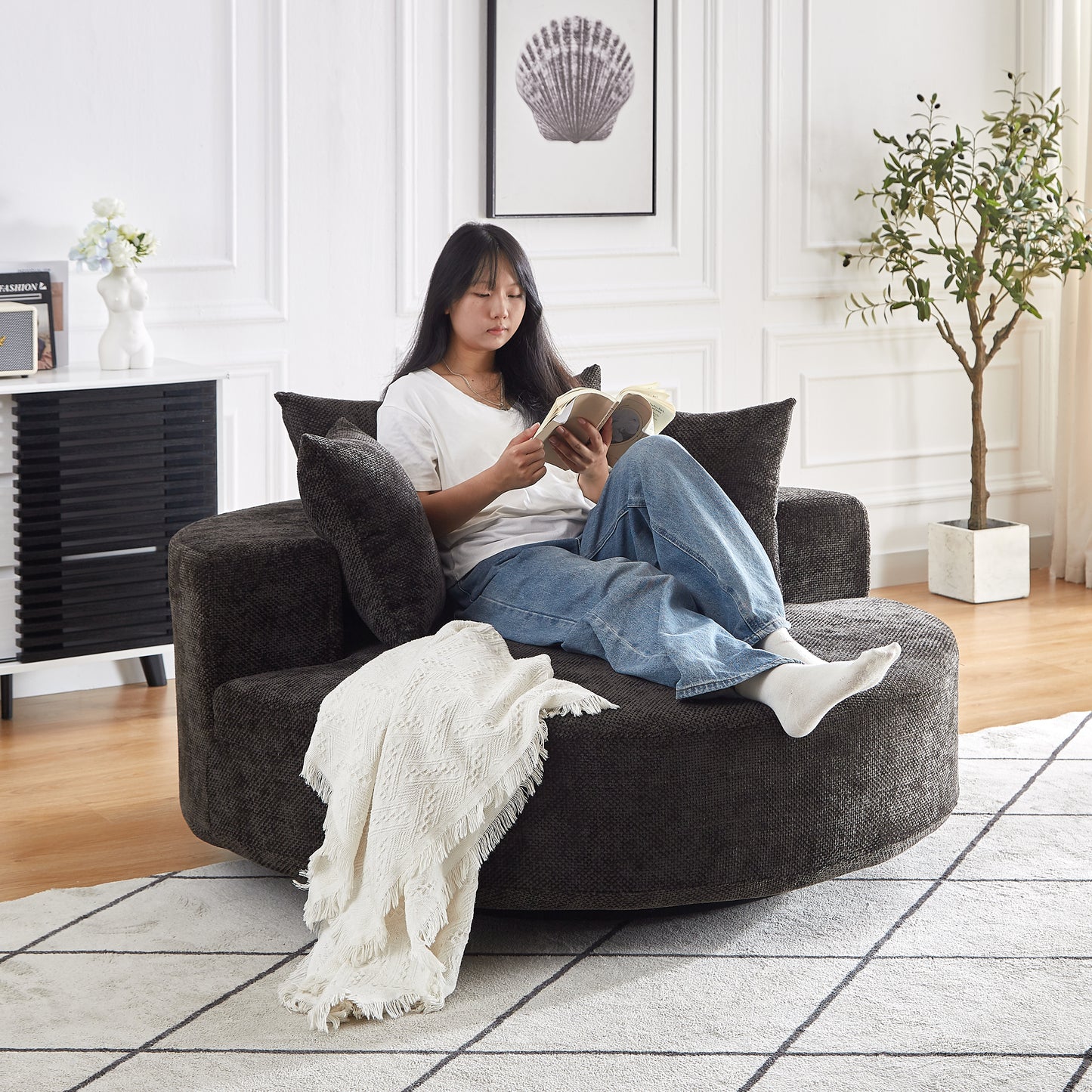 Dark gray textured swivel armchair with plush cushions and a white throw blanket