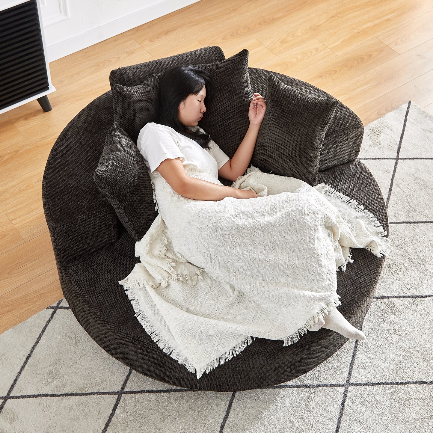 Cozy circular dark gray fabric sofa with plush cushions and a woman napping comfortably