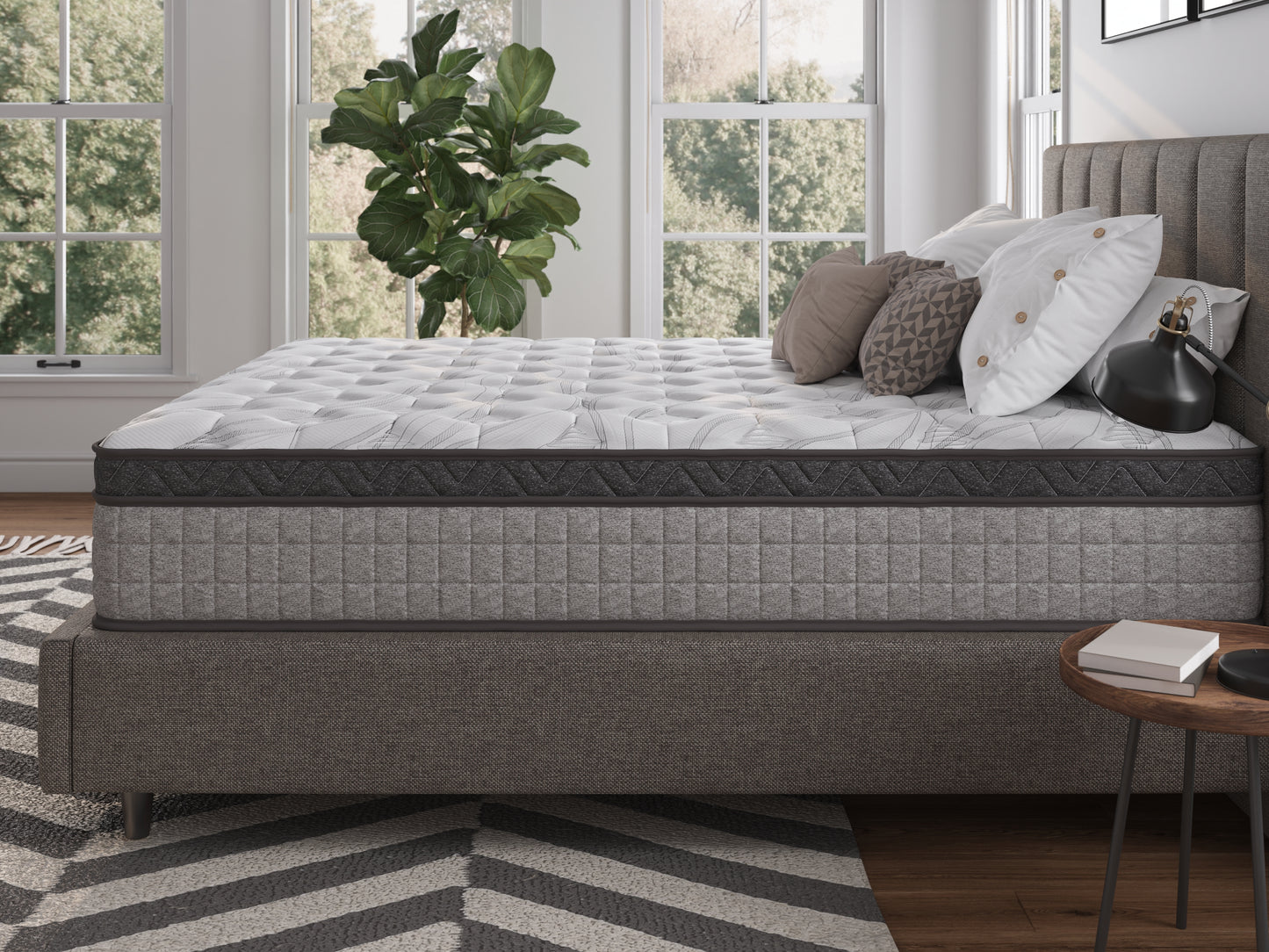 Grey quilted hybrid mattress with dark grey border detail on a bed
