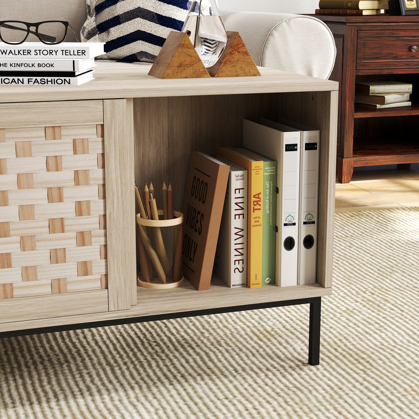 Light oak wood cabinet with woven door panel and black metal legs holding books
