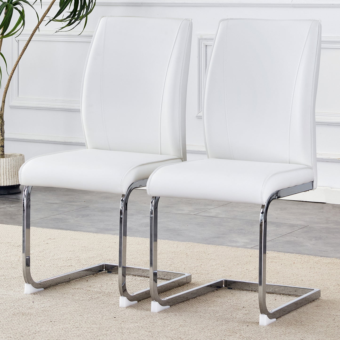 Two white faux leather dining chairs with chrome cantilever bases