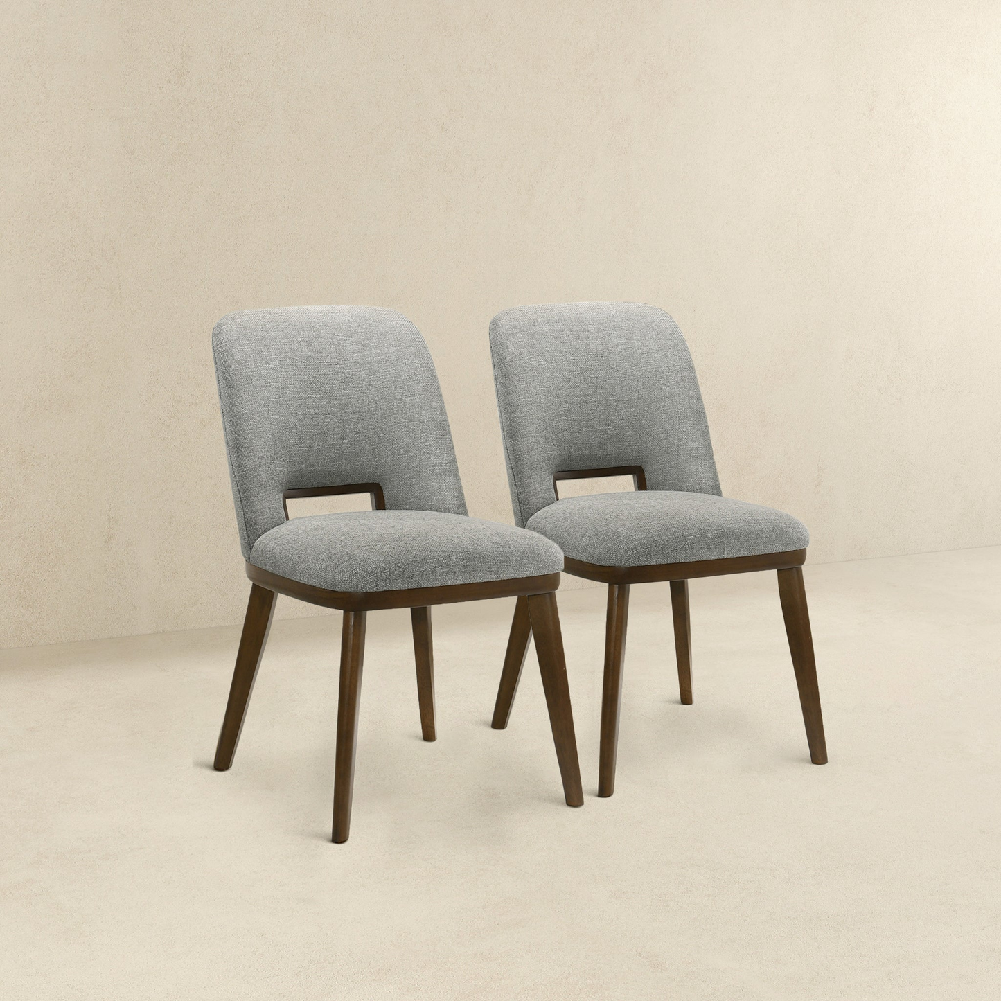 Two upholstered dining chairs with light grey fabric and dark wood legs