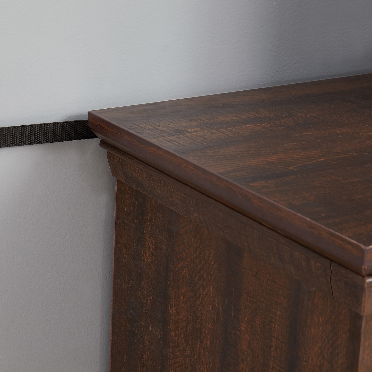Closeup of a dark wood dresser top with distressed texture and carved detailing