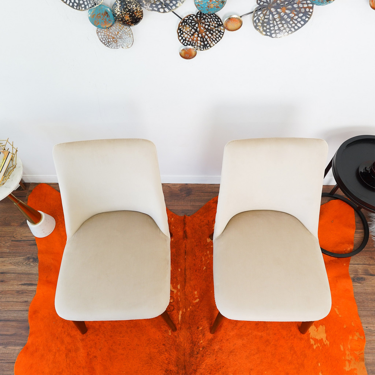 Two cream upholstered accent chairs with curved backs on an orange cowhide rug