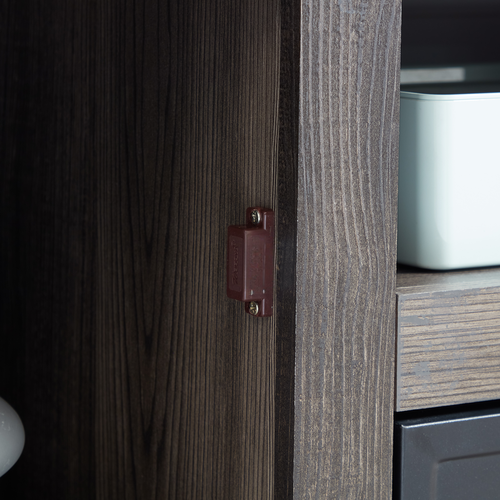 Dark brown magnetic cabinet latch with screws on wood grain door