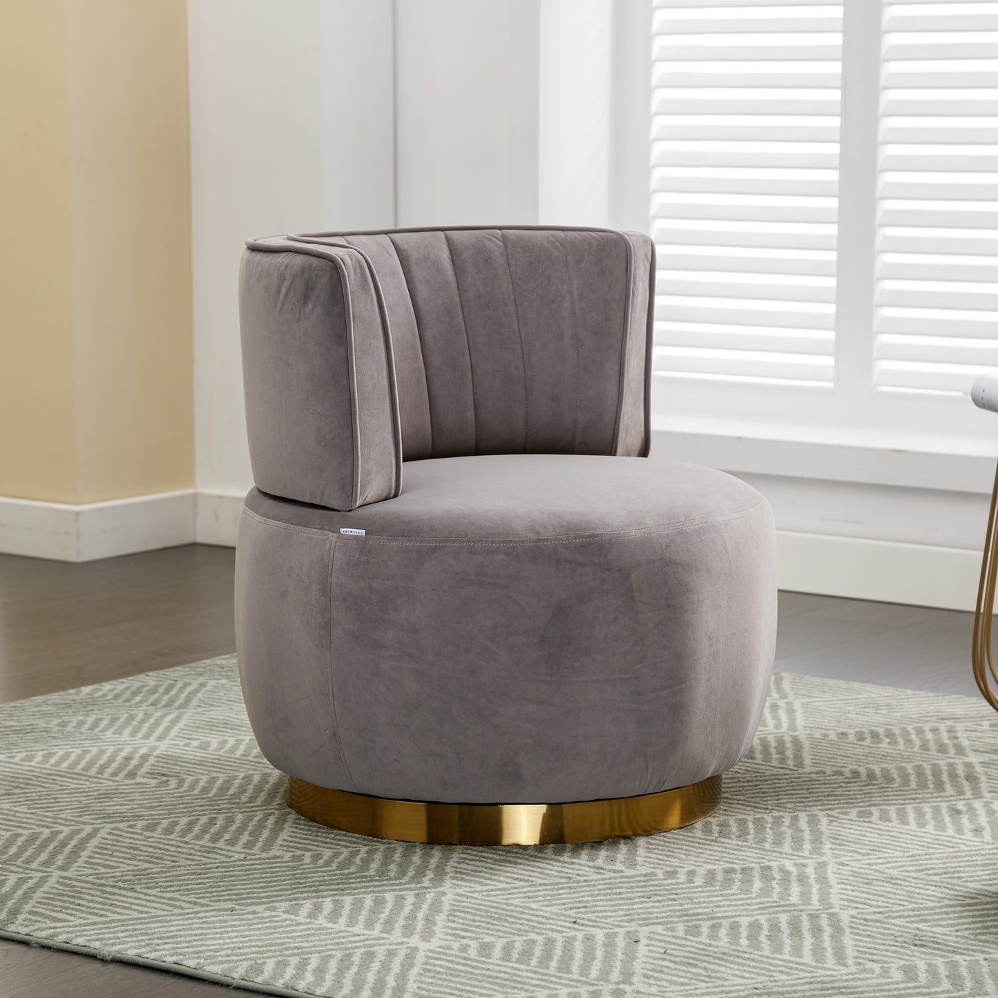 Gray velvet accent chair with plush cushioning and a gold swivel base