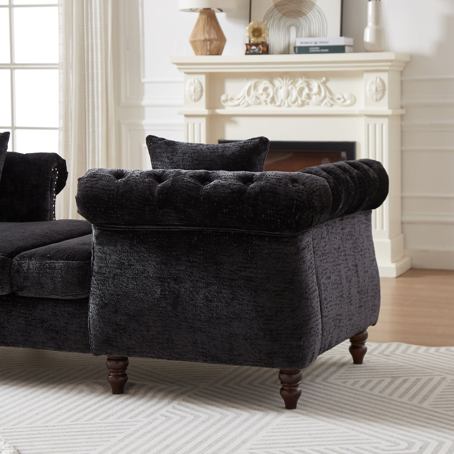 Black tufted velvet sofa with ornate wooden legs and studded armrest detail