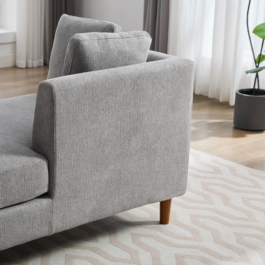 Closeup of a grey textured fabric sofa armrest with wooden legs