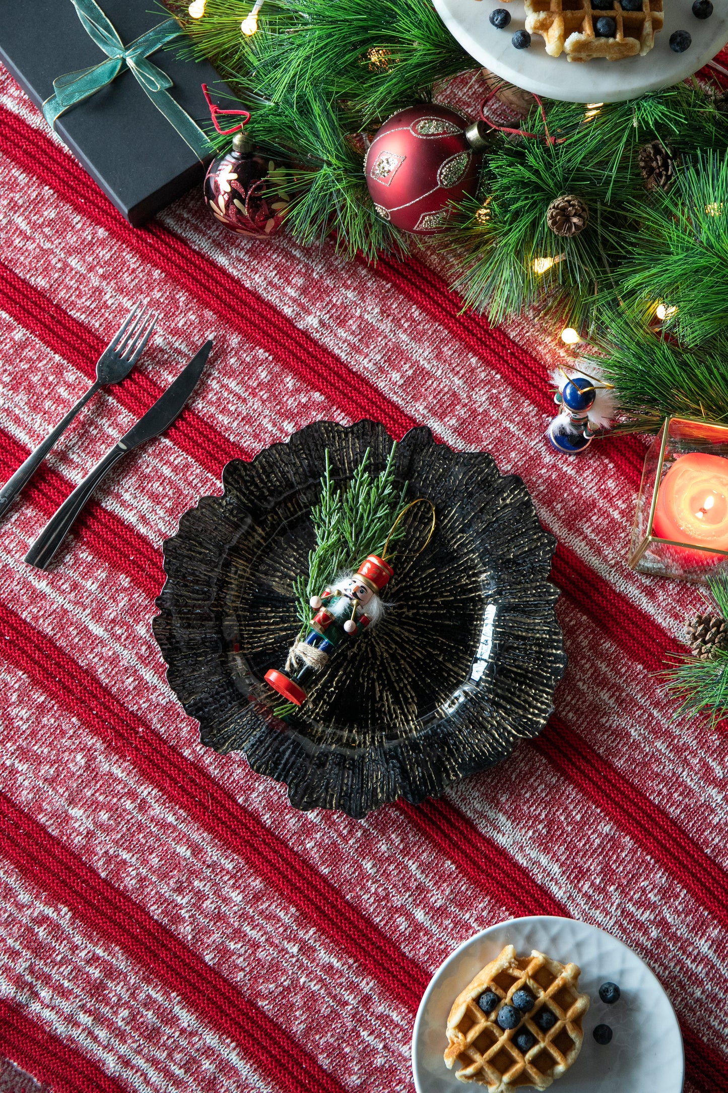 Decorative nutcracker ornament with red hat and green uniform on a festive plate