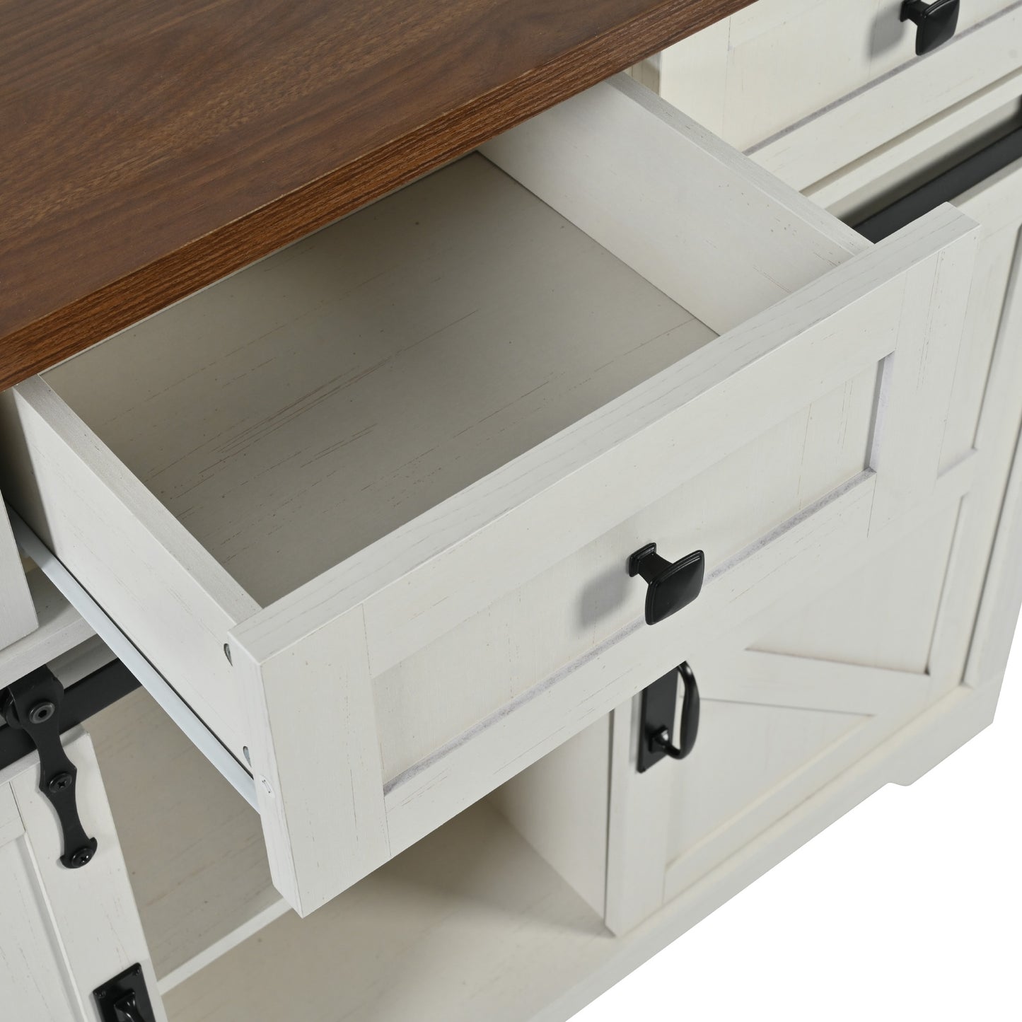 White farmhouse cabinet with distressed finish and dark metal handles open drawer detail