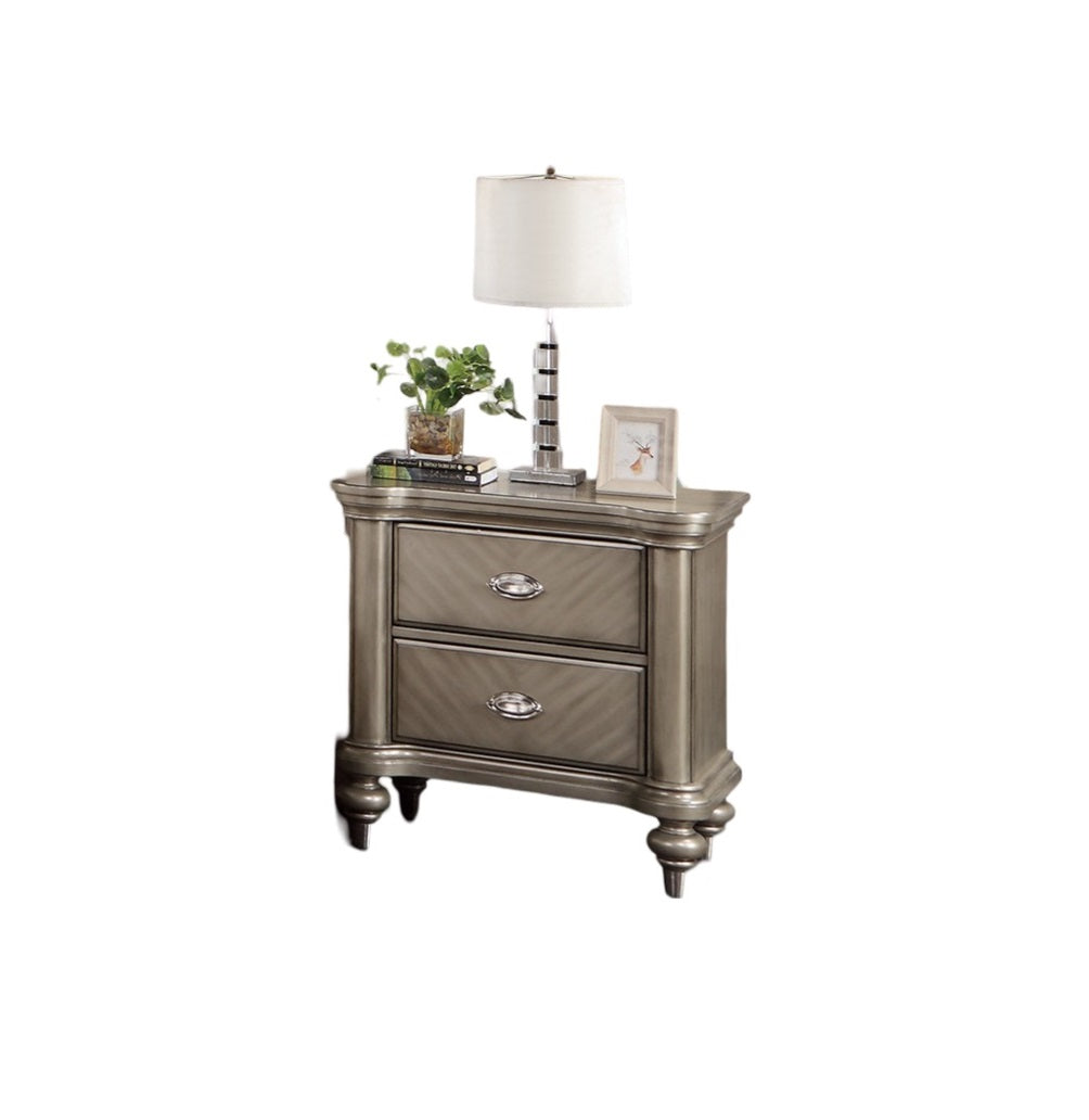 Champagne metallic nightstand with two drawers featuring ornate hardware and carved details