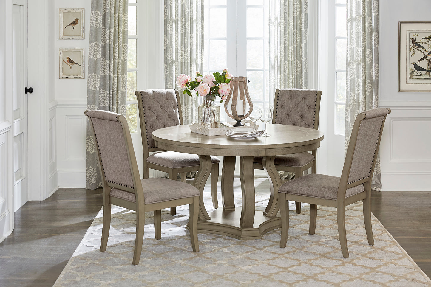 Round dining table with upholstered chairs set for a meal with floral arrangement