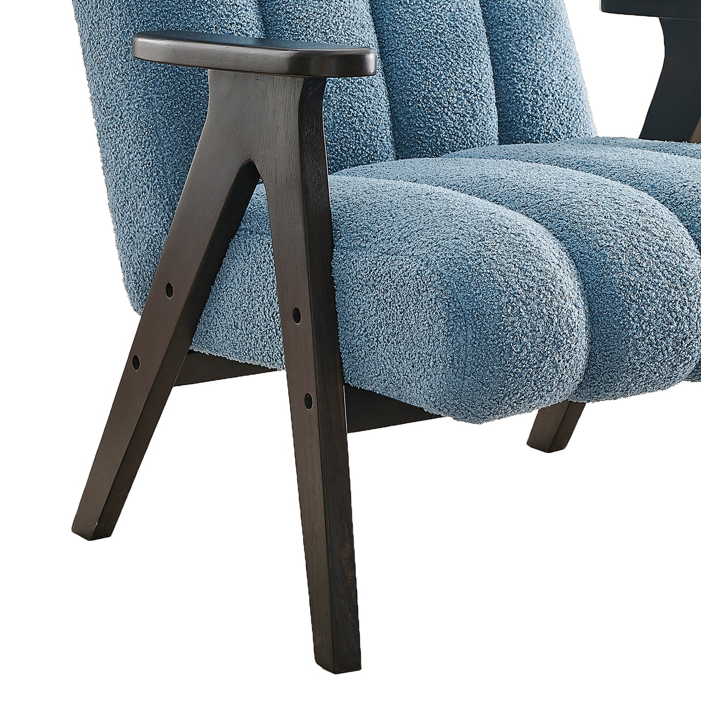 Closeup of a plush blue boucle armchair with dark wood legs showcasing its textured upholstery