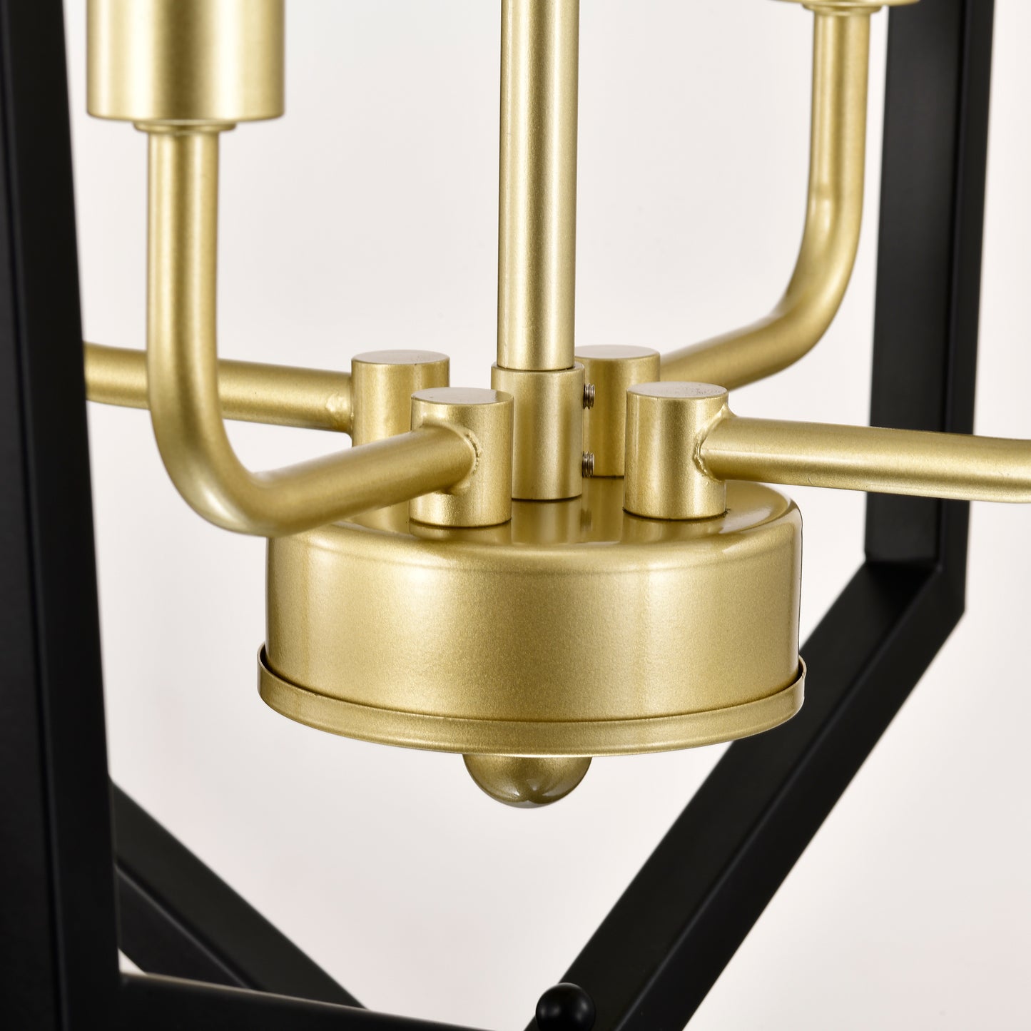 Closeup of brushed brass chandelier central hub with black metal frame accents