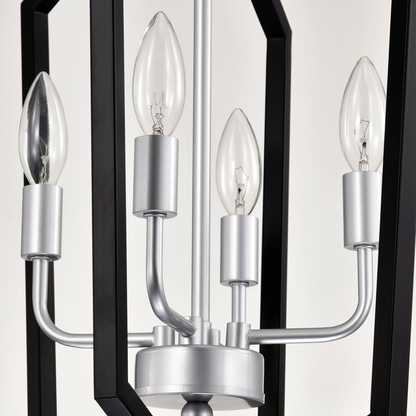 Closeup of a black and silver lanternstyle pendant light with four candle bulbs